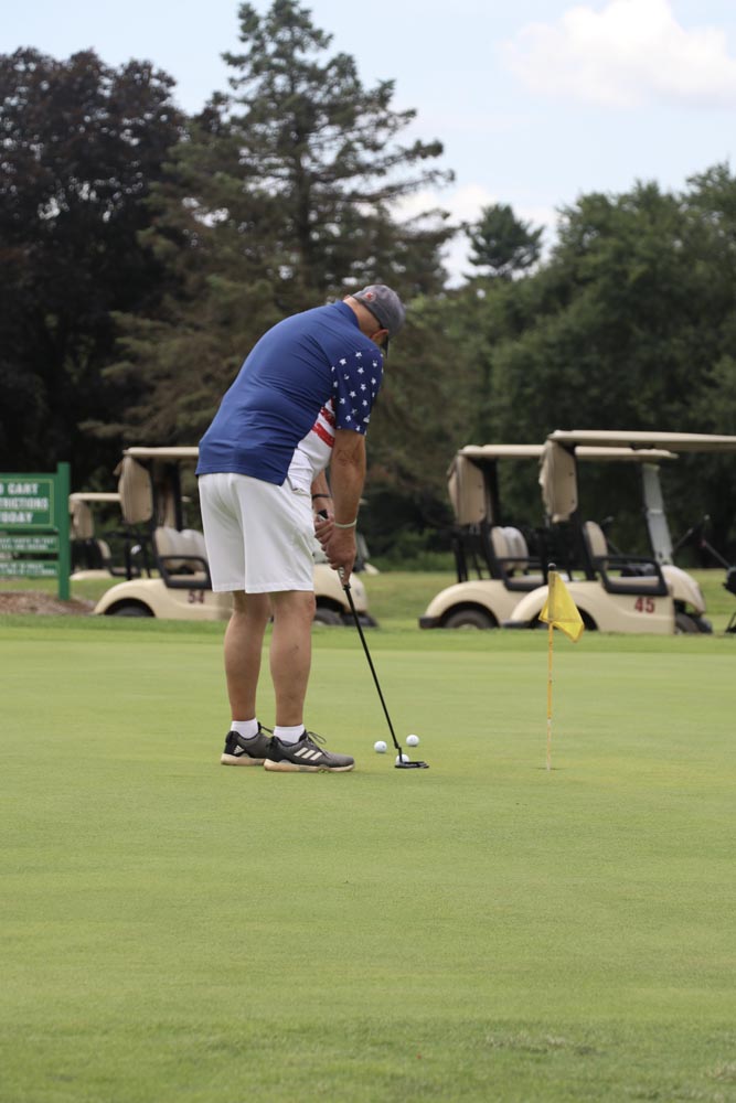 Golfer in blue shirt prepares to tee off